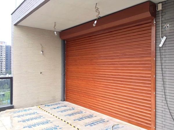 Wood-look aluminum roller door with overhead housing and side guides